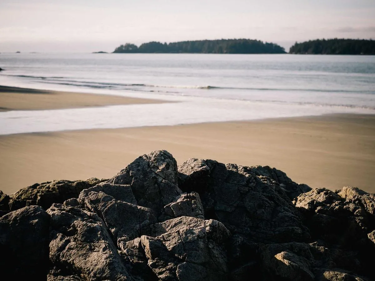 A rocky beach in soft morning light, with islands on the horizon.